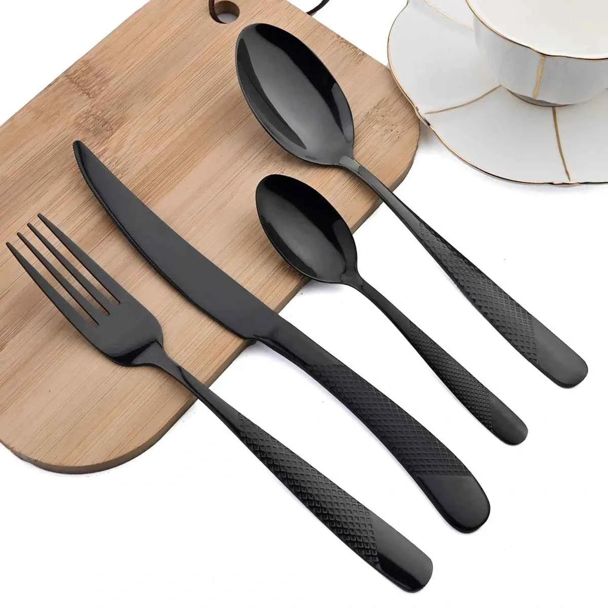Set de couverts 24 pièces noir mat avec manches texturés : gros plan sur le couteau, la fourchette et les cuillères élégantes sur une planche en bois