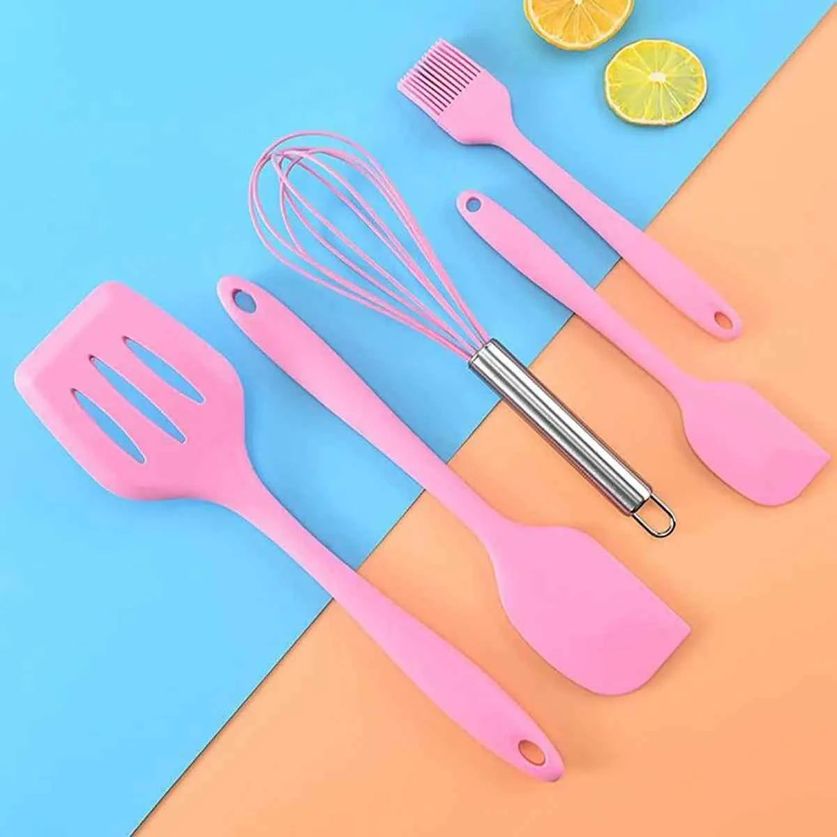 Panoplie de 5 ustensiles de pâtisserie en silicone rose : maryse, spatule, pinceau et fouet présentés sur un fond bicolore moderne