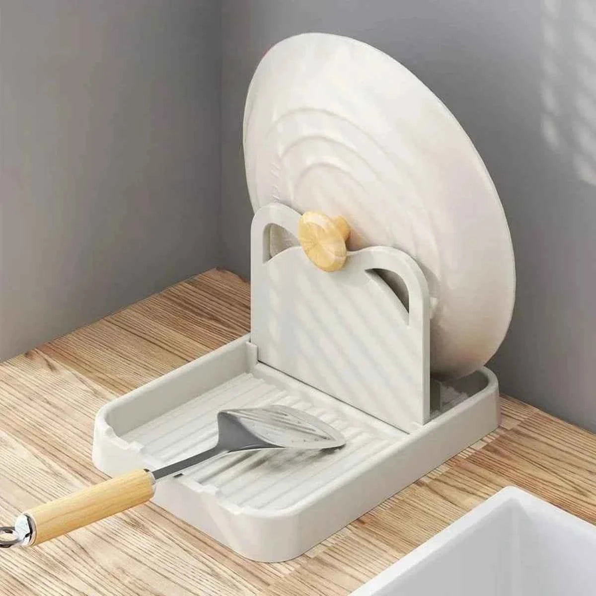 Support de couvercle blanc en silicone avec oreilles de chat supportant un couvercle de casserole et une spatule