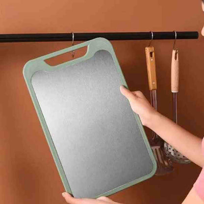 Main tenant une planche à découper grise et verte avec une poignée ergonomique, idéale pour préparer de grands repas