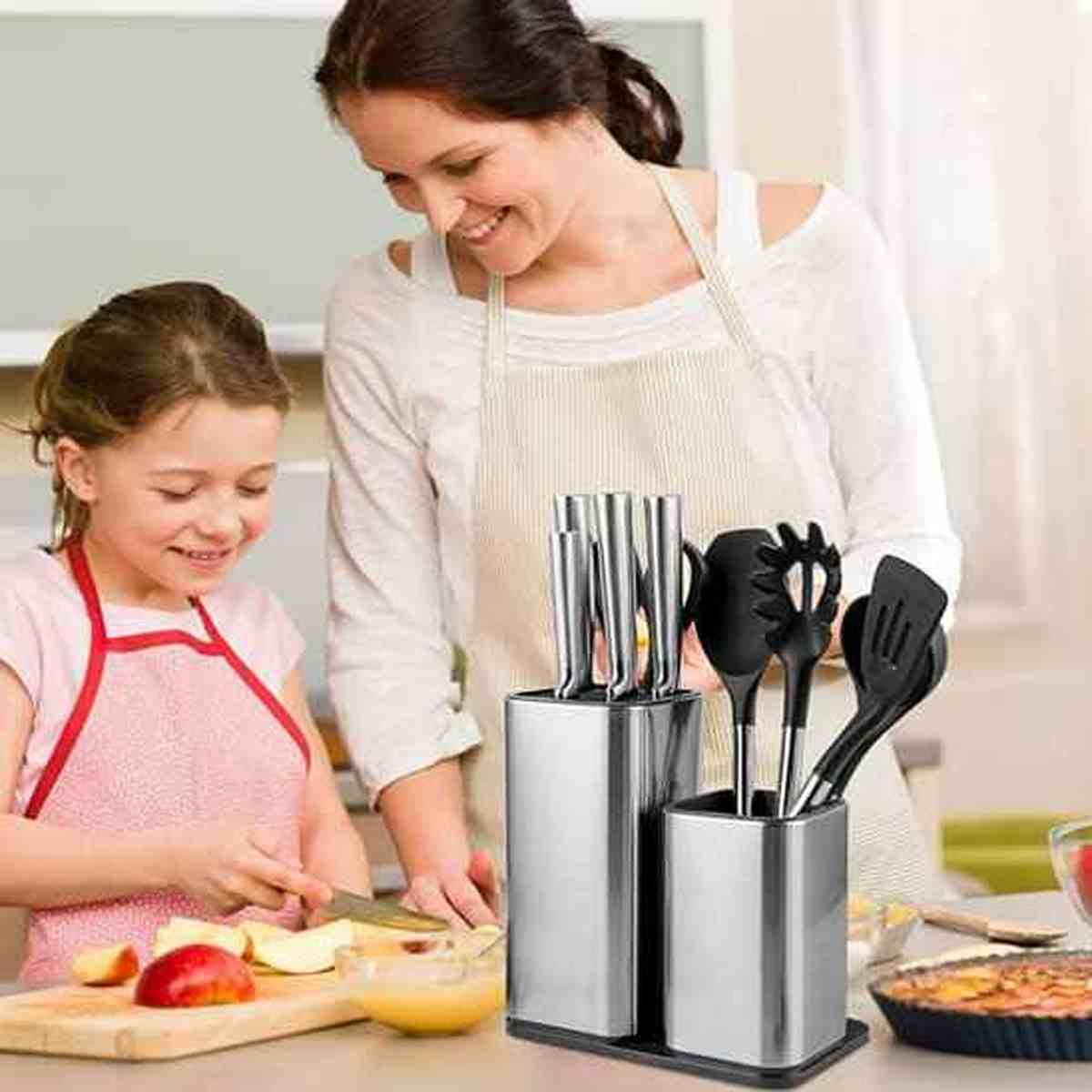 Mère et fille cuisinant à côté du porte-couteaux et ustensiles en acier inoxydable, illustrant un plan de travail rangé et sécurisé.