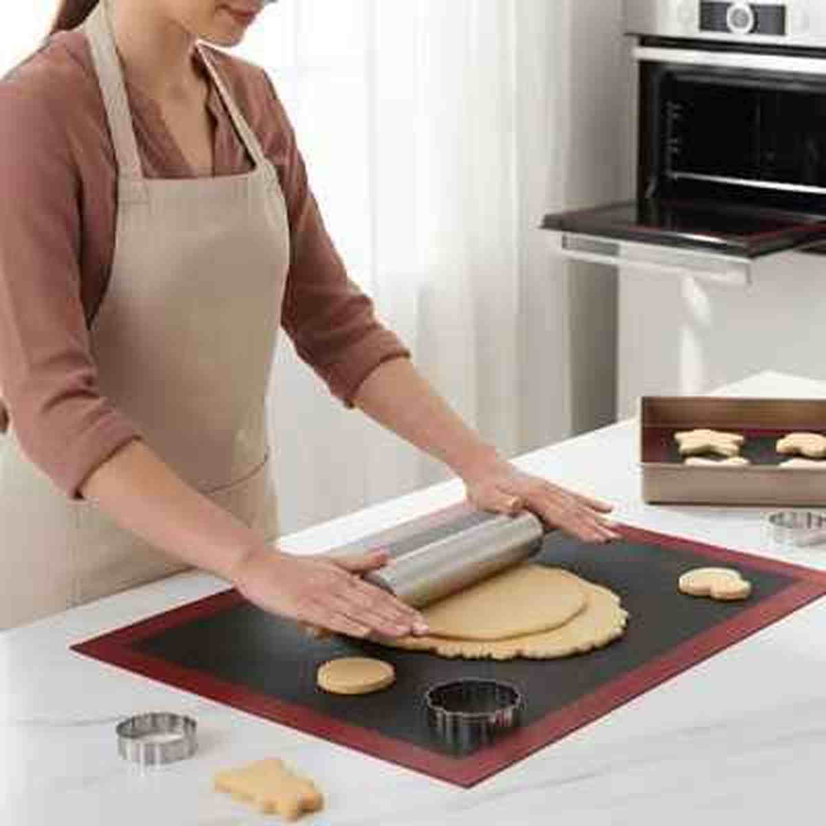 Étaler de la pâte avec un rouleau en inox sur le tapis de cuisson en silicone noir PâtissiPro, une alternative durable et élégante pour la cuisine.