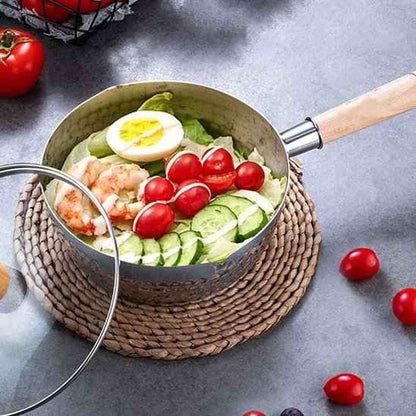 Casserole en acier inoxydable martelé avec couvercle en verre et manche en bois, contenant une salade composée fraîche.