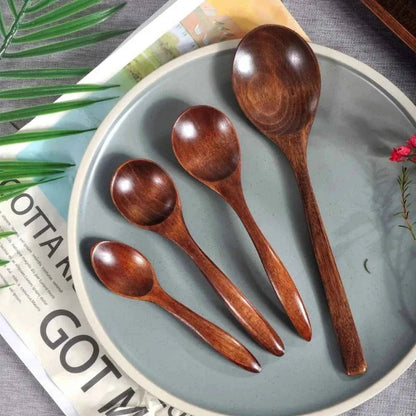 Alignement de quatre cuillères en bois artisanales de différentes tailles (13cm, 15cm, 17cm et 20cm) sur une assiette décorative, montrant le veinage naturel du bois