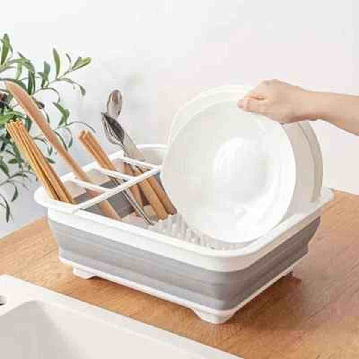 Égouttoir à vaisselle pliable blanc Compact Kitchen rempli d'assiettes et de couverts, posé sur un plan de travail.
