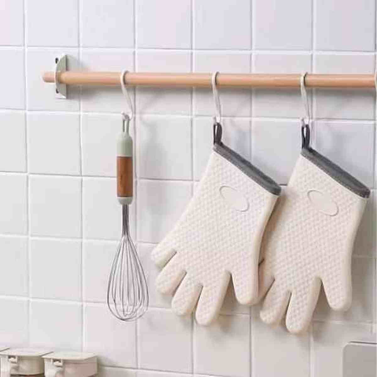 Paire de gants de cuisine ThermoProtect beiges suspendus à un rail de rangement, illustrant le gain de place et l'accessibilité dans une cuisine moderne.