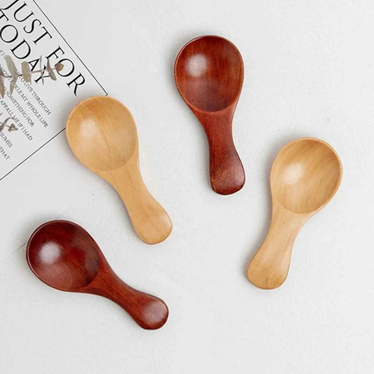 Vue de dessus de quatre mini cuillères en bois disposées en éventail, montrant les nuances de bois clair et bois sombre