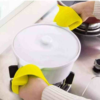 Mini manique en silicone jaune ThermoShield utilisée pour soulever le couvercle d'une marmite chaude sur une cuisinière.
