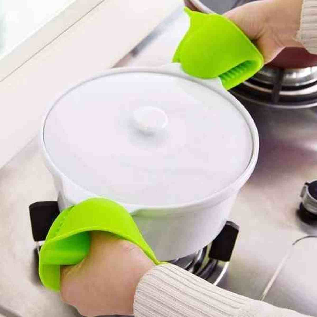 Utilisation de deux mini maniques en silicone vert ThermoShield pour soulever en toute sécurité une cocotte chaude par ses poignées