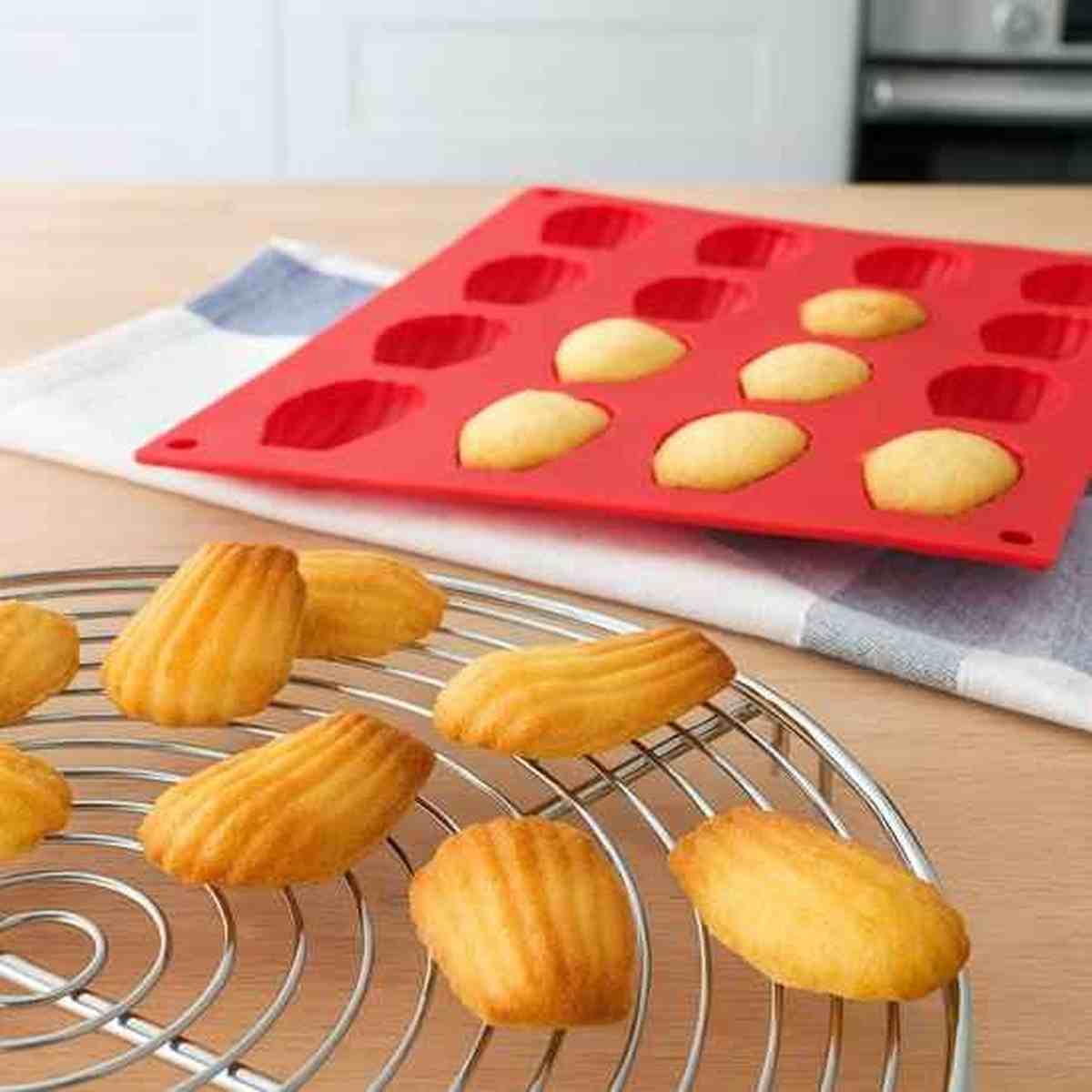 Moule à madeleines en silicone rouge avec 12 empreintes, idéal pour un démoulage parfait et des madeleines dorées avec une belle bosse.