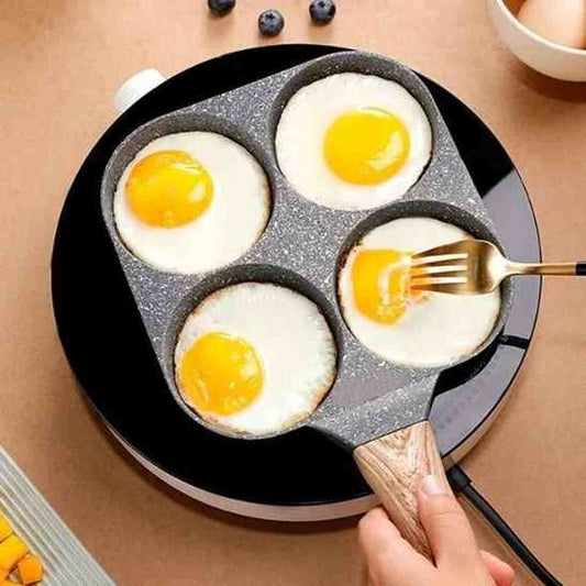 Poêle à œufs et pancakes 4 compartiments en action sur une plaque à induction avec quatre œufs au plat parfaitement cuits.