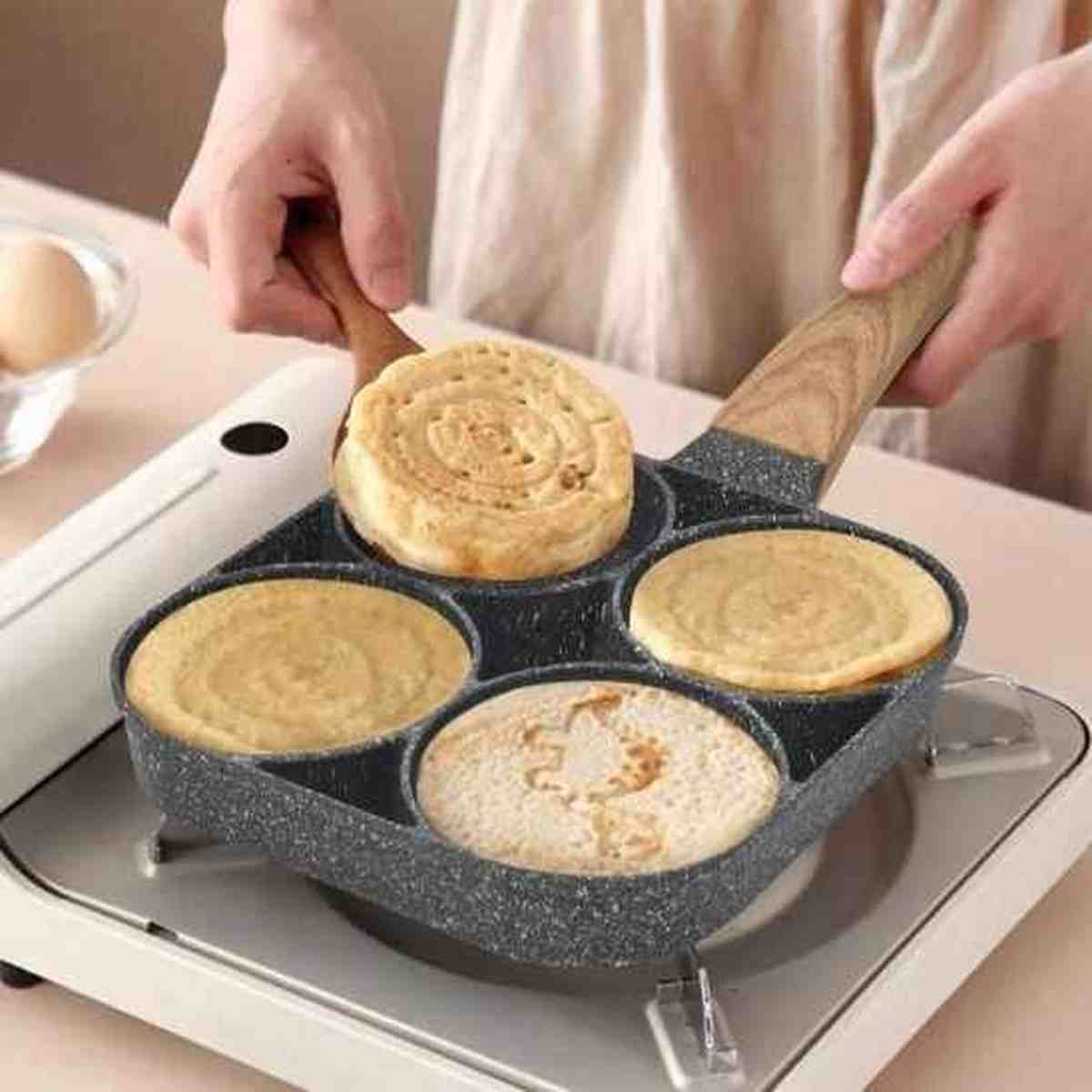 Cuisson de pancakes épais dans une poêle PerfectCook 4 compartiments sur un réchaud à gaz portable.
