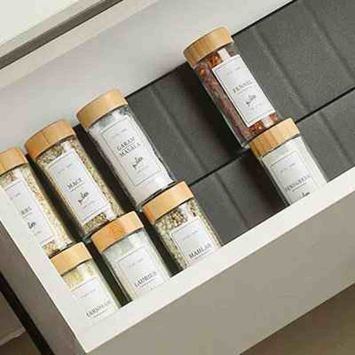 Organisateur de tiroir pour épices extensible OrganizPro avec flacons en verre dans un tiroir de cuisine moderne.