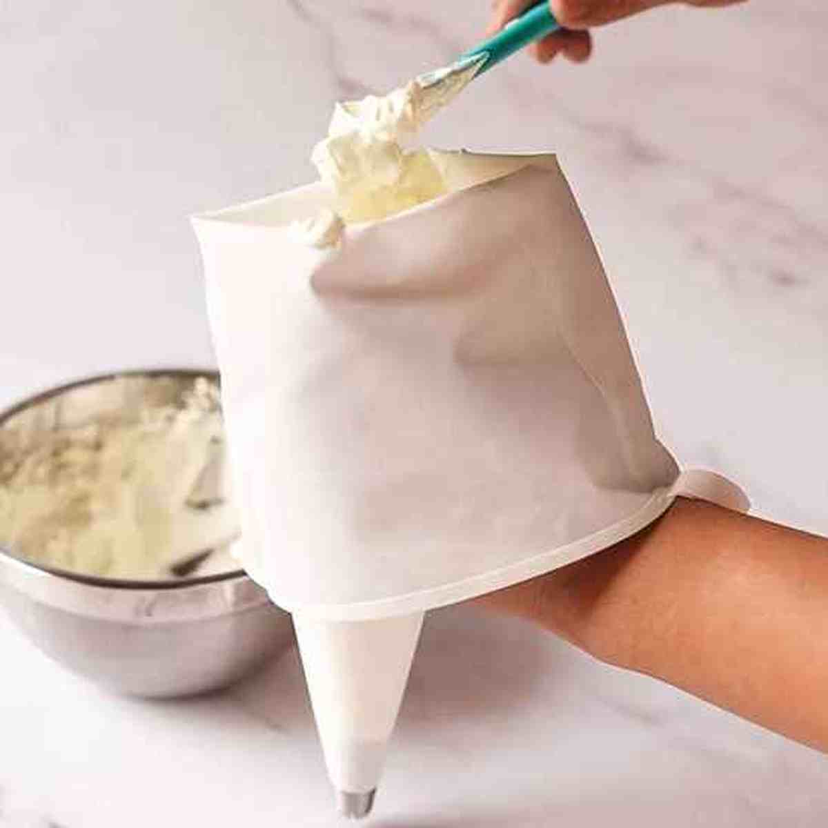 Remplissage d'une poche à douille Pâtissier Pro avec une spatule, illustrant la souplesse du silicone et la facilité de préparation.