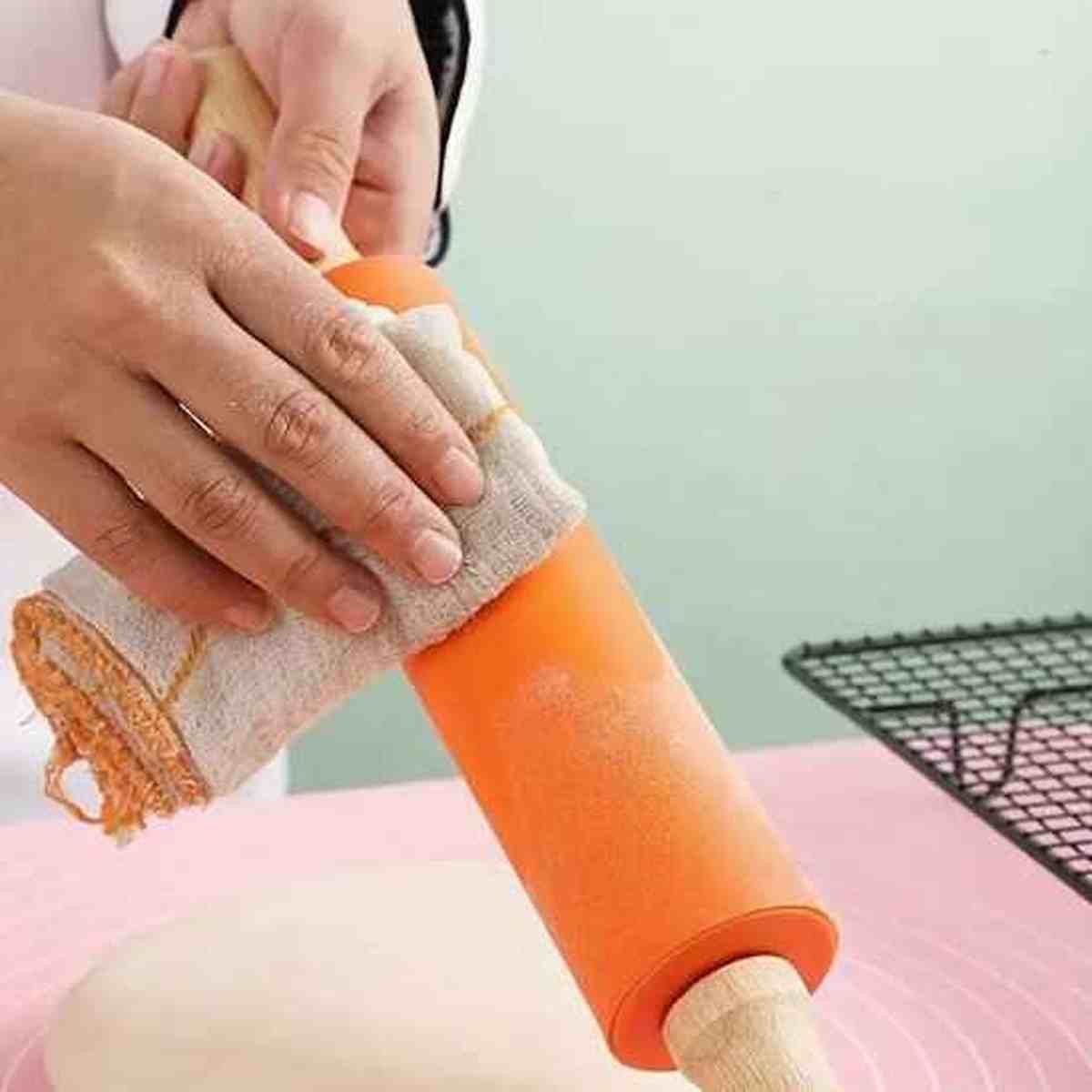 Utilisation du rouleau à pâtisserie en silicone orange Artisan Pro pour étaler une pâte délicate avec l'aide d'un linge de cuisine.